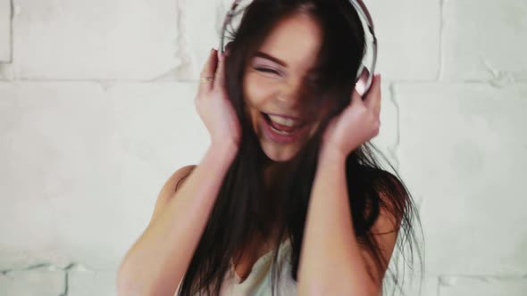 Young Happy Woman Is Listening Music in Headphones, Waving Head and Dancing