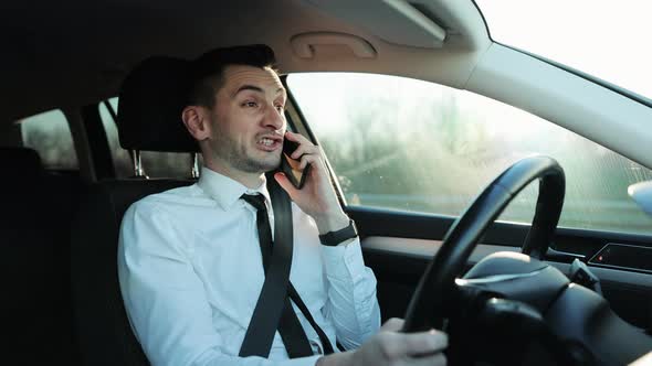 Handsome Concentrated Talking Man Driving Car and Using Smartphone for Call