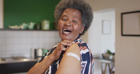 Happy senior african american senior woman showing plaster on arm after covid vaccination alt