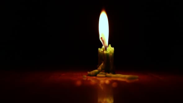 A single green candle burning.Isolated candle burning with dark background.