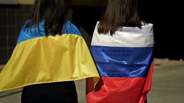 Women with Flags of Russia and Ukraine on Their Shoulders Turned Away From Each Other