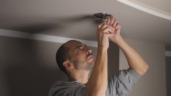 A Man Installs a Ceiling Ice Lamp in the House