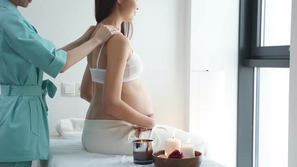 Adorable Chinese Pregnant Female Getting Spa Massage on Back Hugging Tummy
