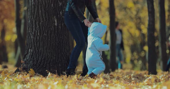 Happy Mother Holds the Child By the Hand and Walks in the Autumn Park alt