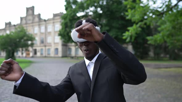 Front View Smiling African American Man in Formal Suit and VR Headset Gaming Online Standing alt