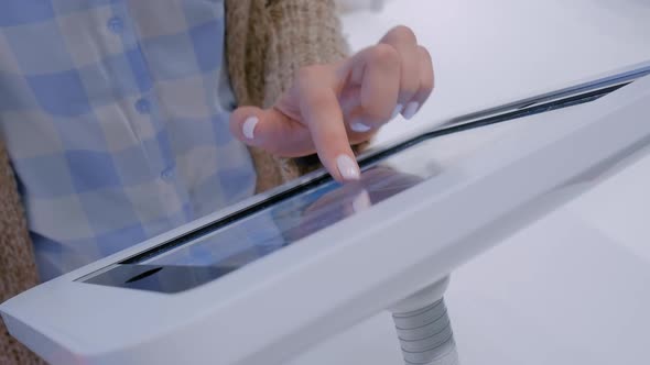 Woman Hand Using Touchscreen Display of Floor Standing White Tablet Kiosk
