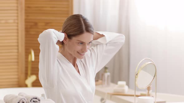 Pretty Positive Middle Aged Lady Making Ponytail Hairdo at Home Looking at Mirror at Bathroom Slow alt