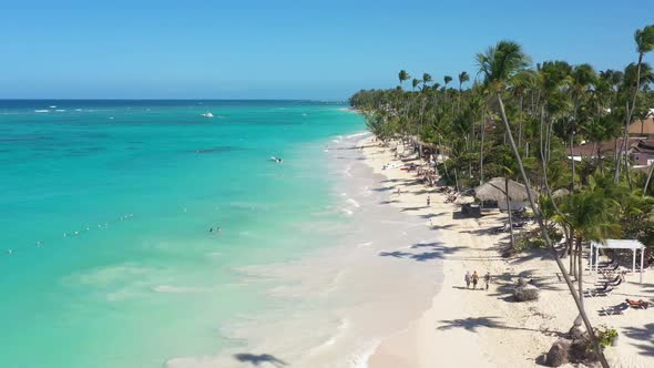 Tropical Coastline with Resorts Palm Trees Caribbean Sea and People Having Fun on Beach alt