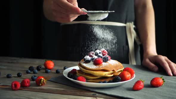 Sugar Powder Being Poured Over Pancakes Beautifully Served with Berries. Food Art. Dessert and