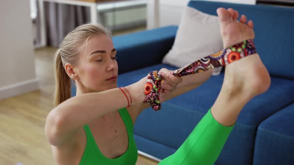 Beautiful Slim Girl Stretching Legs with the Help of a Belt alt