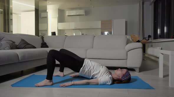Sports Girl Performs Footwork Exercise While Lying on Blue Yoga Mat at Home