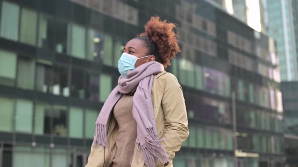 Young black woman putting on medical mask and then taking off against cityscape alt
