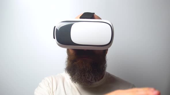 Bearded man use virtual reality headset helmet on white background. VR. Virtual reality glasses. alt