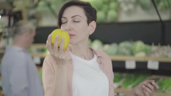 Portrait of Beautiful Woman Smelling Organic Yellow Bell Pepper and Smiling. Positive Young alt