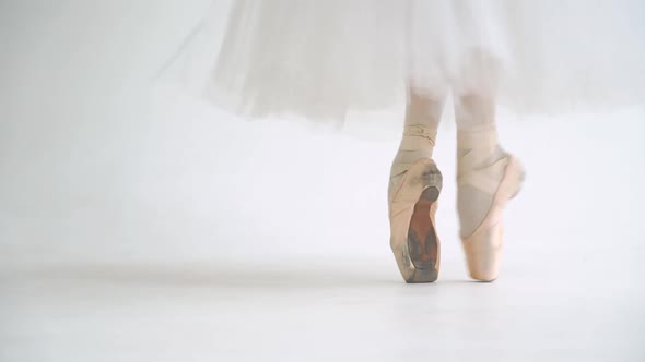 Female in a White Tutu Dance Ballet and Balancing in Pointe Shoes View of the Legs White Background alt