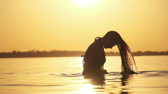 Silhouette of Woman Flipping Her Long Hair Back in Water. Slow Motion 240 Fps alt
