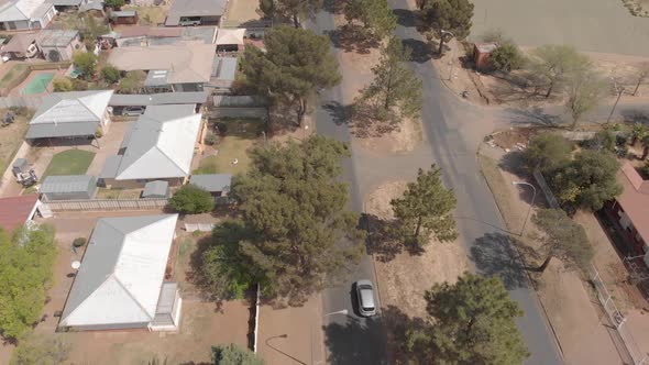 aerial shot of a car drving in a residential suburb alt