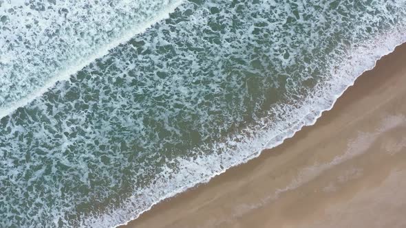 Aerial view of waves crash to beach