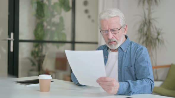 Senior Old Man Reacting to Loss While Reading Documents in Office alt