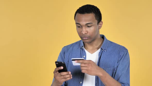 Online Shopping on Smartphone By Young African Man Yellow Background alt