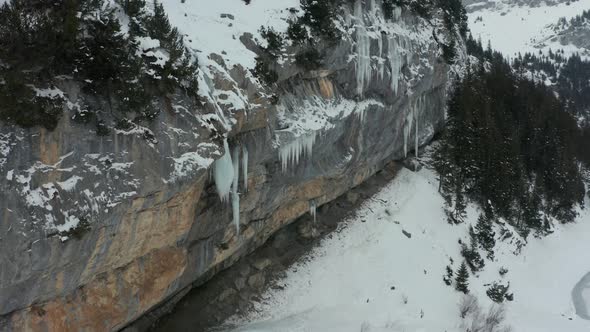 Jib down of melting icicle on the edge of mountain alt