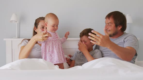 Happy Family with Cute Little Kids Son Daughter Tickling Having Fun Relax on Bad Together Young alt