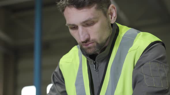 Close-up Face of Concentrated Brown-eyed Caucasian Man in Green Vest Looking Down. Professional alt