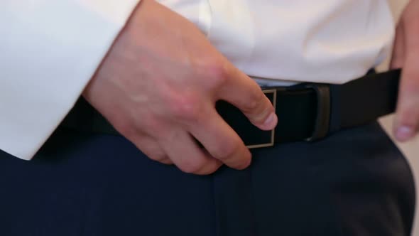 Man Fastens the Belt on His Trousers Closeup alt