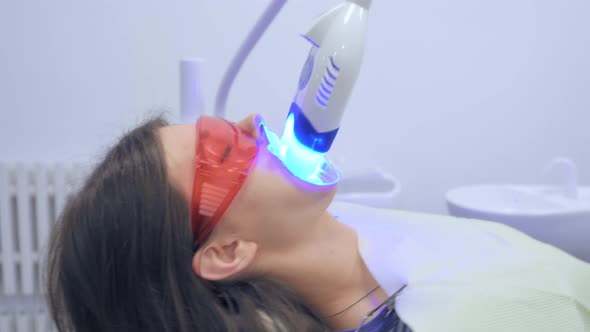 Close Up Woman at Teeth Whitening Procedure in Dental Office
