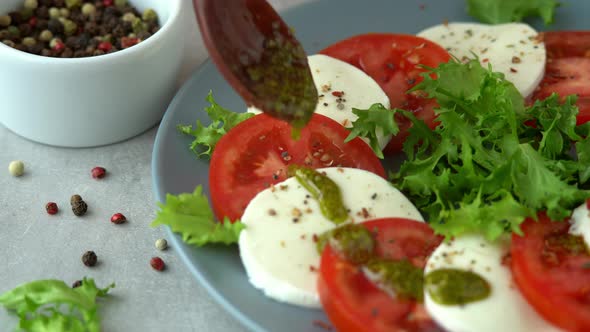 Salad with Mozzarella Cheese Tomatoes and Lettuce is Poured Sauce Basil Pesto From Spoon alt