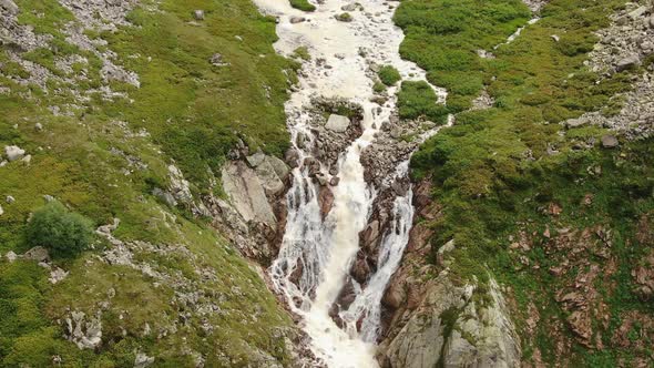 Waterfall Falls Down Along Sharp Rocks From Mountain Height alt