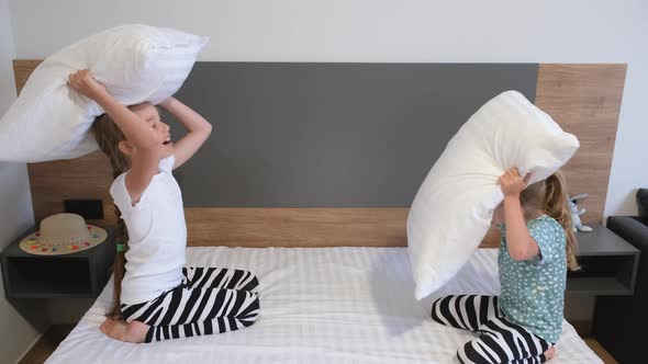 Two Cute Children Siblings Girls Playing Pillow Fight on Bed