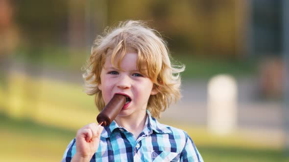 Young Blond Boy Eating a Ice Cream on a Stick Outdoor