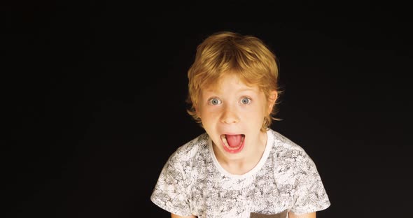 Young boy screams in front of black background