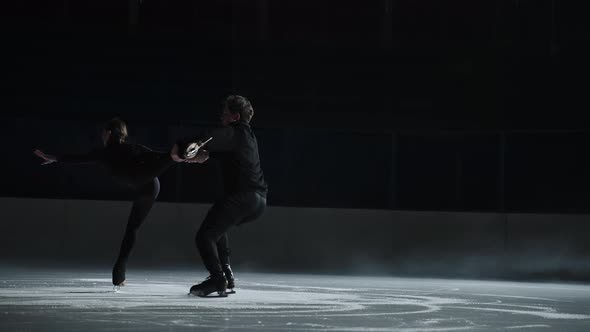 Slow Motion Young Couple of Artistic Figure Skaters is Performing a Pair Skating Choreography on Ice alt