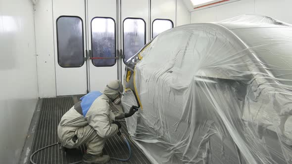 A Man Paints the Wing of the Car