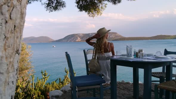 Beautiful Girl Tourist Sitting at Summer Cafe with Sea and Mountains on Background at Ermioni Greece alt
