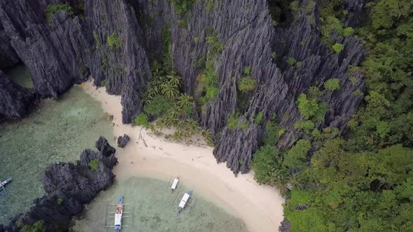 Aerial pedestal down on beach by limestone cliffs at Secret Lagoon in El Nido, Palawan, the Philippi alt