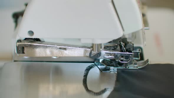 Closeup the Overstitching Machine Passes the Edges of the Black Fabric in Slow Motion alt