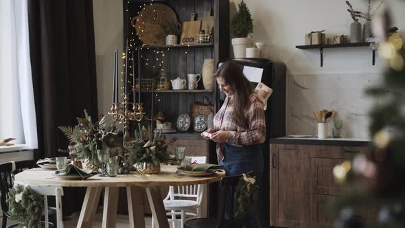 Plump Woman Smiles and Lays Out Serves a Festive Christmas Table Small Gift alt