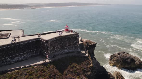 Aerial view Tourists exploring the Nazaré Lighthouse with Seascape as Background alt