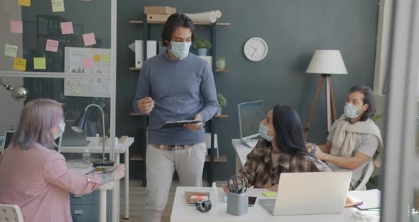 Boss Arab Guy Talking to Diverse Group of People Employees Wearing Medical Masks in Office alt