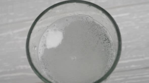 Effervescent aspirin tablet dropping to glass of water. Slow motion fizzy pill falls and dissolves w alt