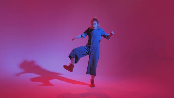 Young Stylish Girl Dancing in the Studio on a Colored Neon Background