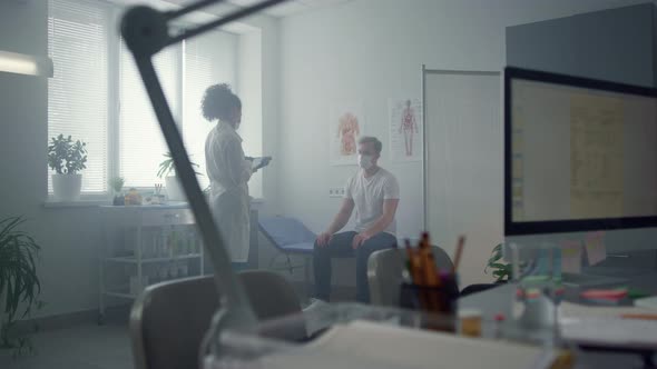Woman Physician Using Tablet Computer Consulting Patient in Hospital Office alt