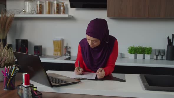 Thoughtful Lovely Middle Eastern Woman Working on Business Startup in Domestic Kitchen alt