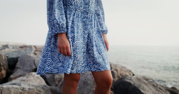 The Wind Develops the Hem of the Woman's Dress Standing on a Rocky Seashore alt