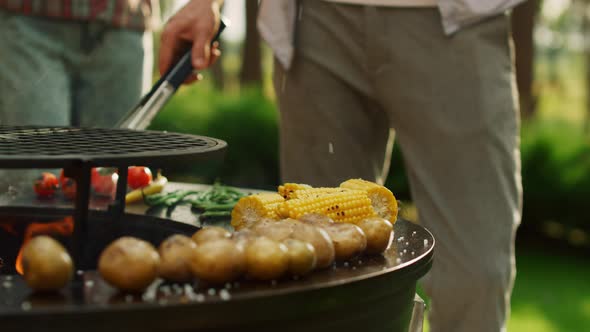 Male Chef Using Forceps for Cooking Food Outdoors alt