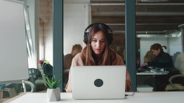 Portrait of Happy Woman Businessperson Young Student in Headphones Looks at Laptop Screen Reads Good alt