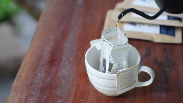 A woman pouring hot water from kettle to make drip coffee